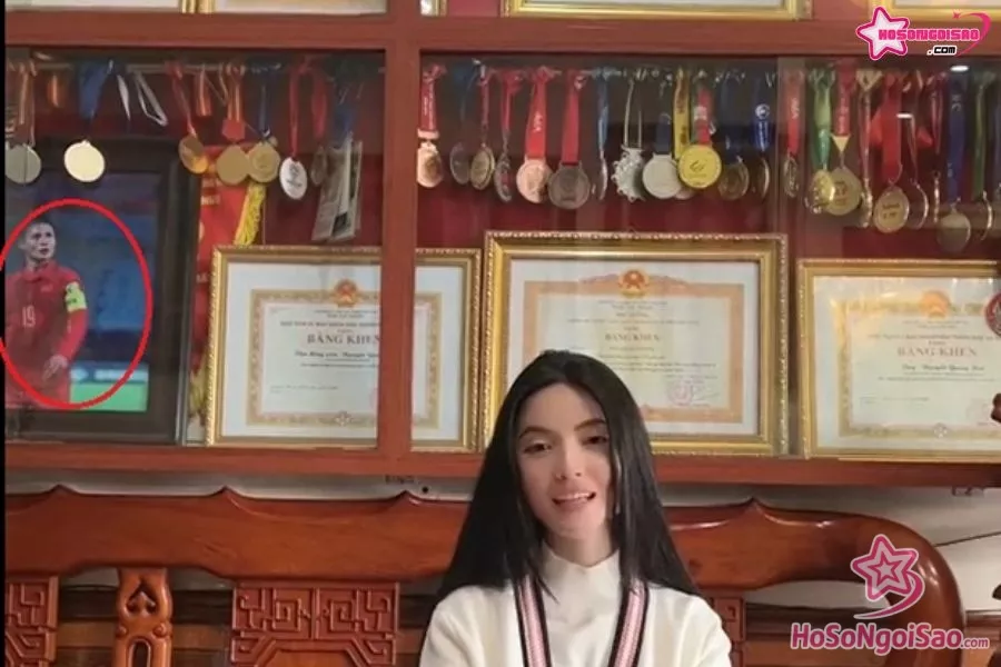 Chu Thanh Huyền ngồi bán hàng với background là huy chương, danh hiệu của Quang Hải